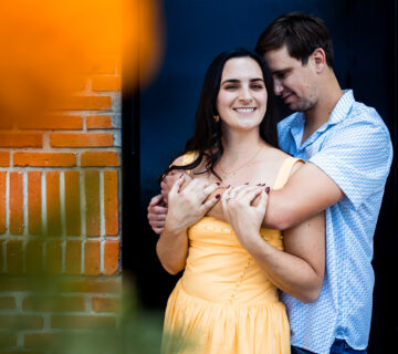 girl and boy hugging in front of a black door in cdmx, girl smile and a orange flower on the side