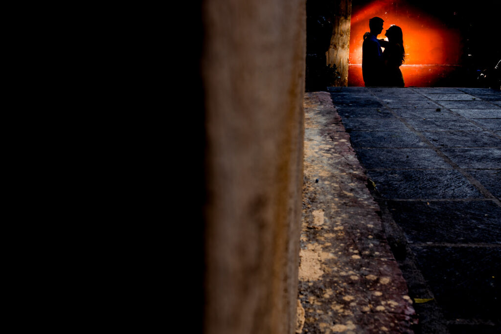 a siluette of a couple in front of a red wall