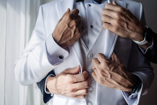 hands are hugging a suit of the groom and the groom is holding his own suit