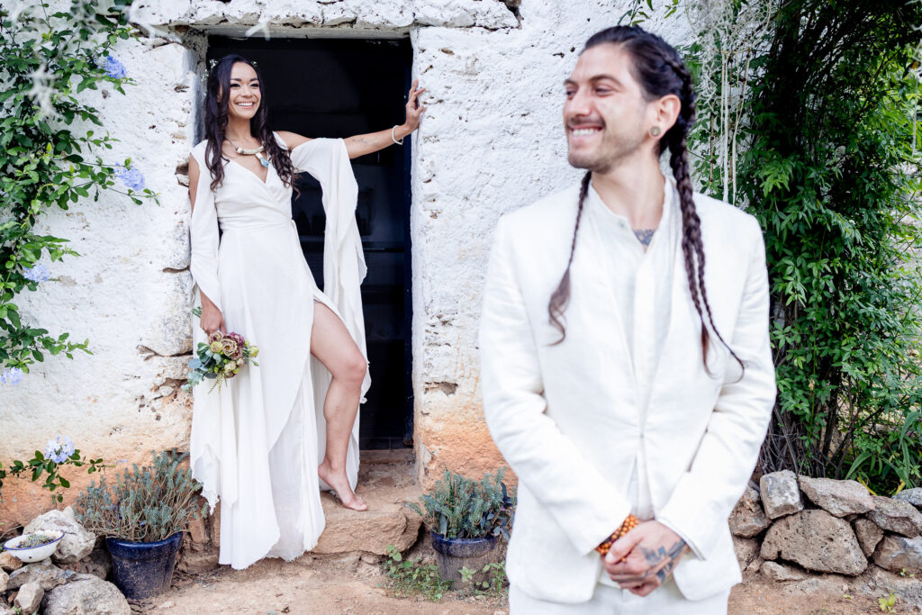 bride on focus on the background is holding her bouquet and smiling on the foreground we can see the groom he is smiling too