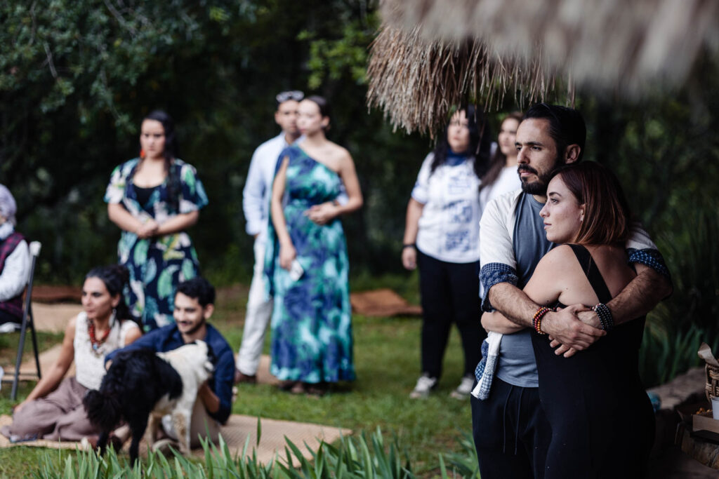 a couple is hugging each other during a wedding ceremony and they are looking to the couple