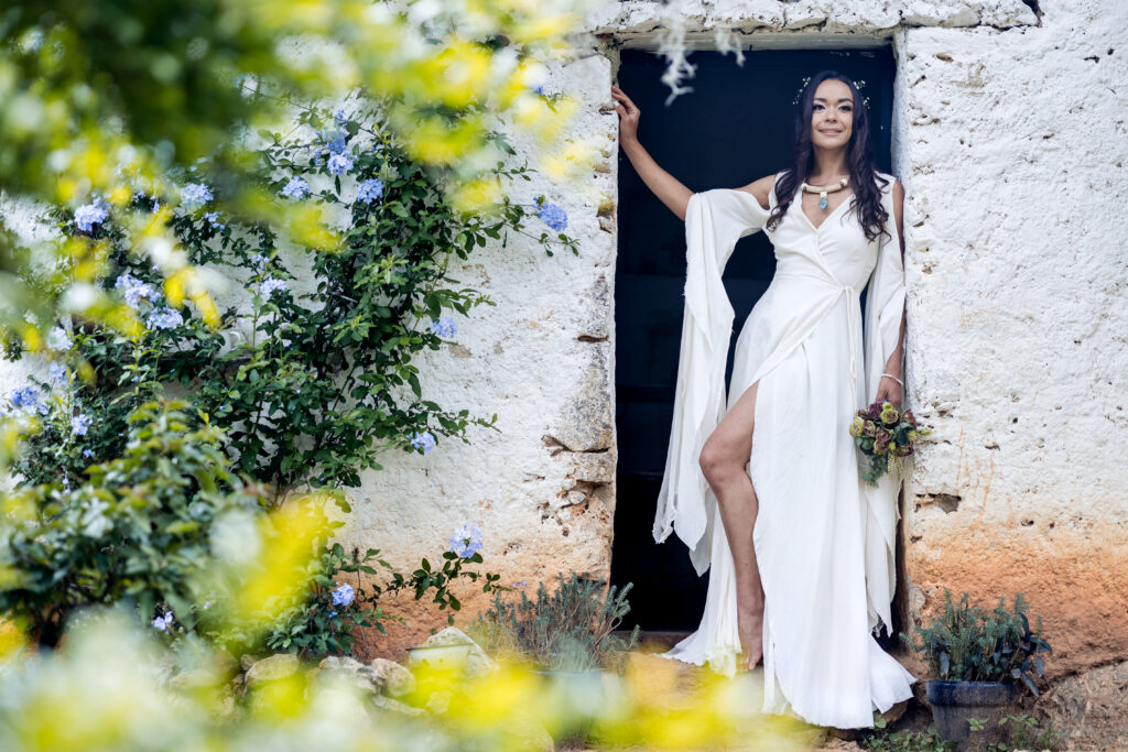 a bride with a stunning white dress is in front of a door and smiling to th camera