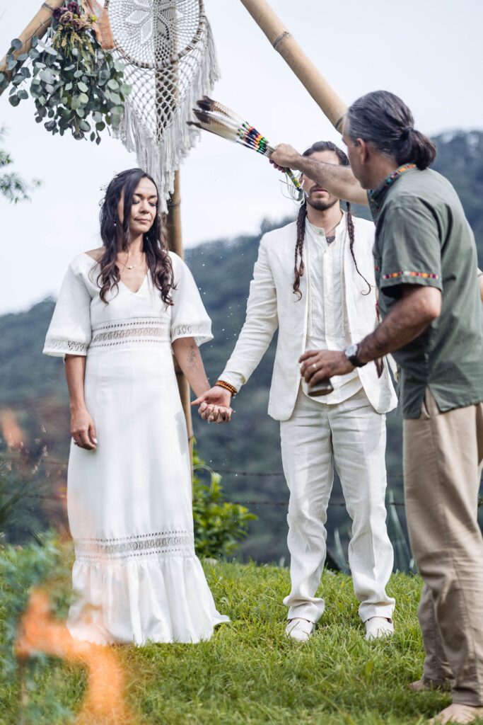 bride and groom during the ceremony they are holding hands and the minister is blessing them 