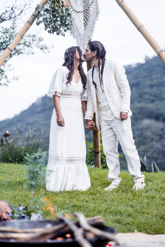 bride and groom are kissing each other during the ceremony and with a fire on the foreground