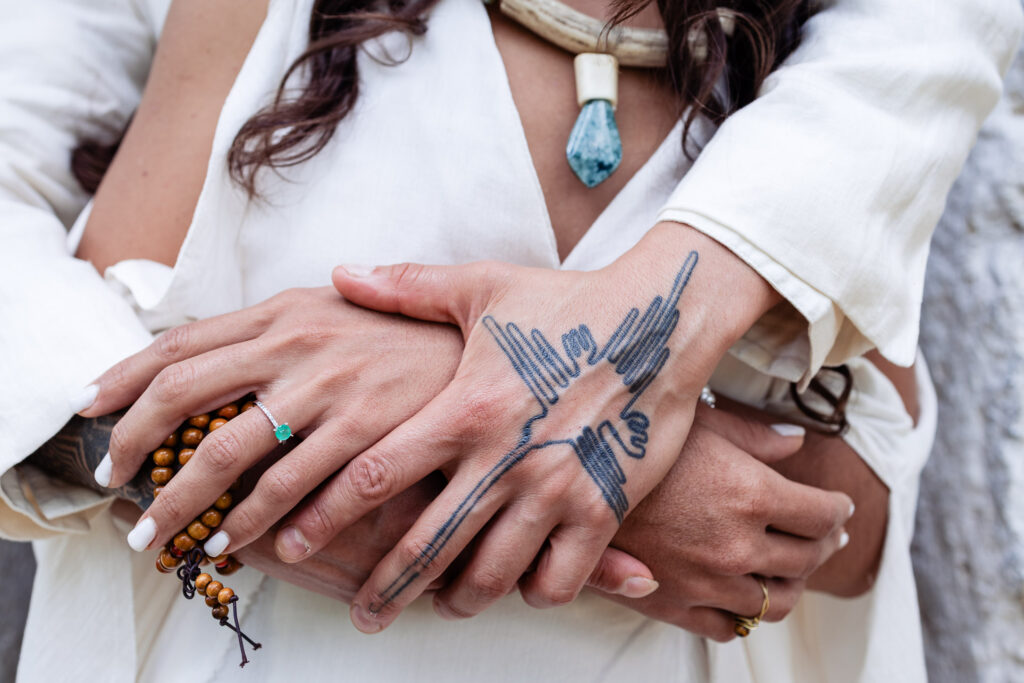 details of the hands of the bride and groom touching each other, the hand of the groom have a tattoo on it